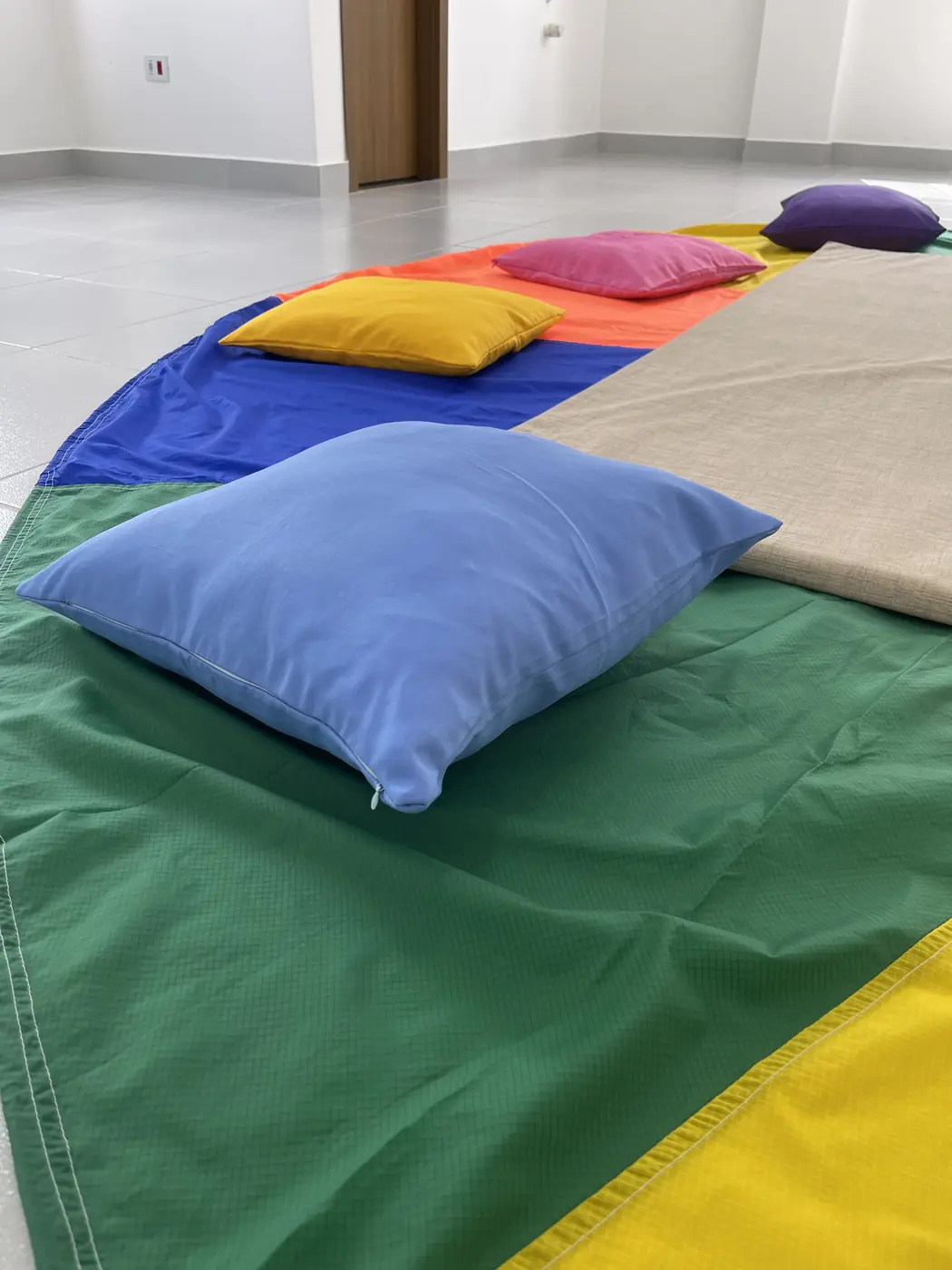 Almofadas e tecidos coloridos usados nas brincadeiras, espalhados pelo chão do salão