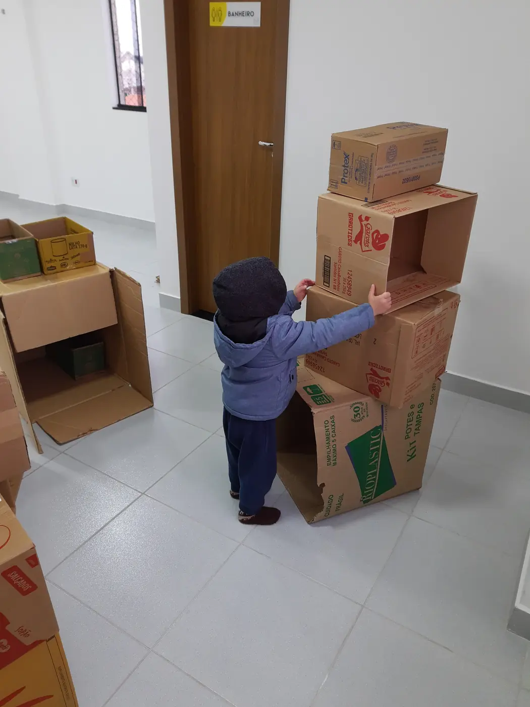 Criança de costas empilhando caixas de papelão durante uma sessão de Psicomotricidade Relacional